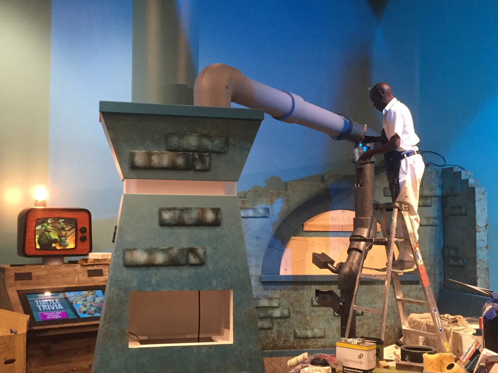 Person on ladder working on exhibit installation.